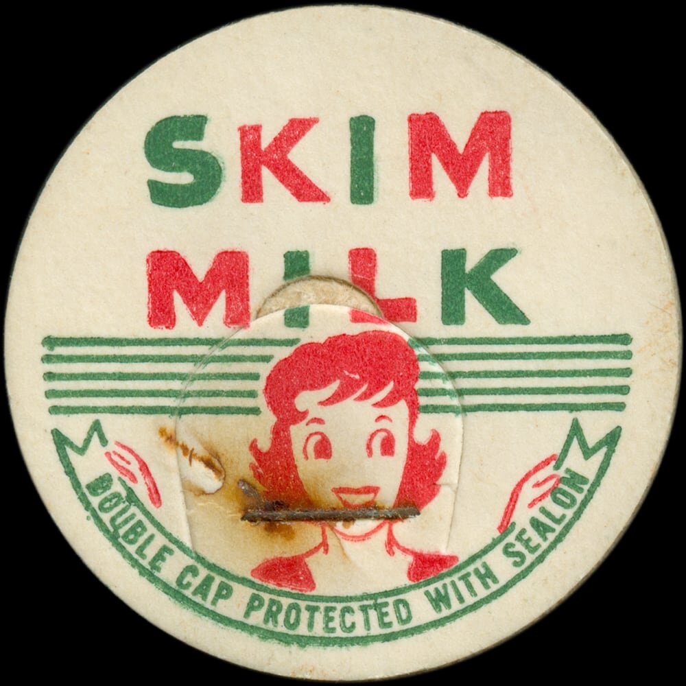 Vintage circular dairy cap with printed typographic milk advertising and a metal pull tab.