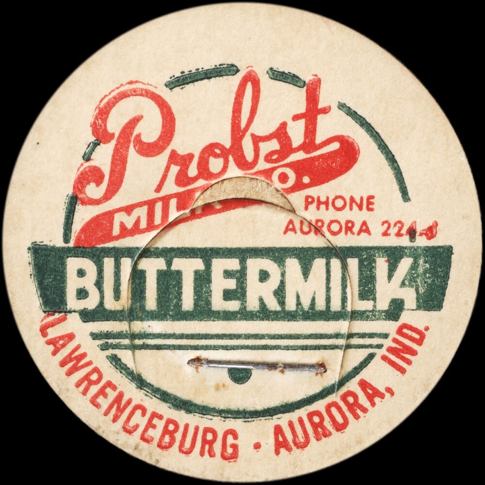 Vintage circular dairy cap with printed typographic milk advertising and a metal pull tab.
