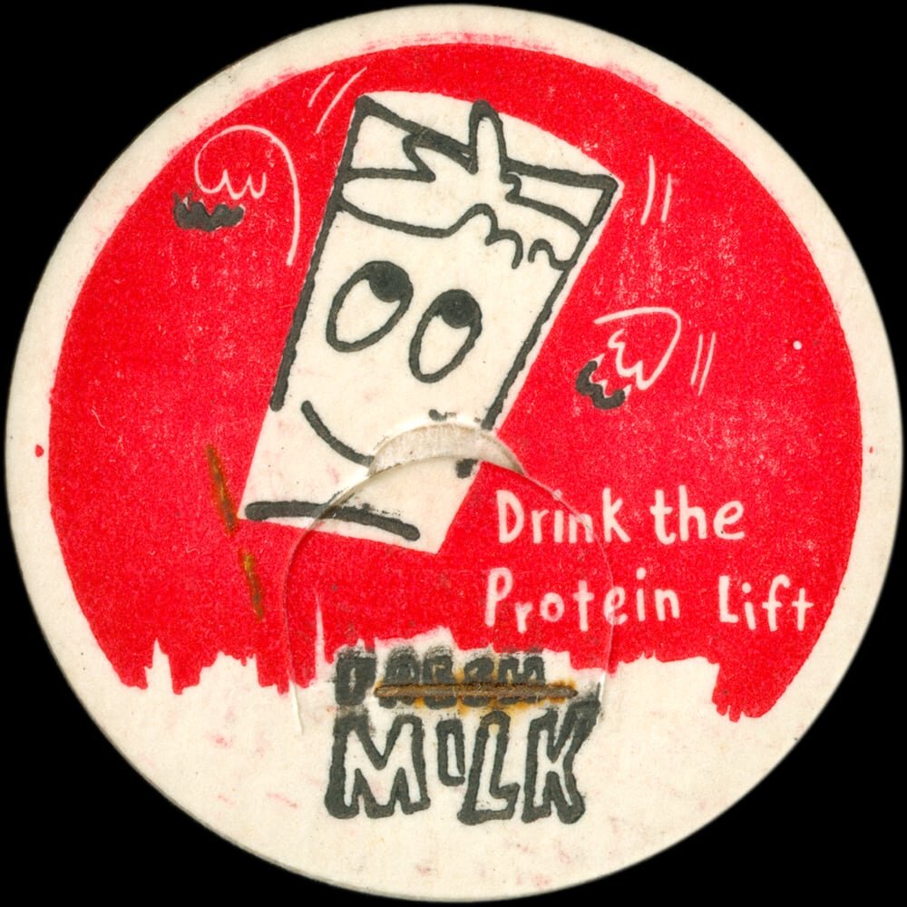 Vintage circular dairy cap with printed typographic milk advertising and a metal pull tab.